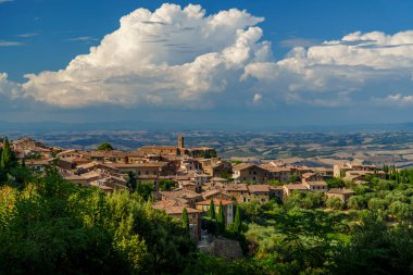Geleneksel Toskana kasabası, terracotta çatıları ve yemyeşil tepeler, güzel İtalyan manzarası üzerinde dramatik bir gökyüzü..