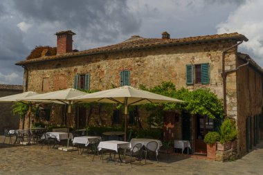 Yeşil kepenkleri, açık masaları, şemsiyeleri, tırmanma sarmaşıkları, tarihi Toskana.