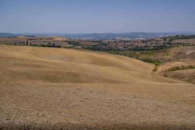 Geniş kuru tepeler, uzak bir köy ve dağ ufkuna uzanan yumuşak yamaçlar..