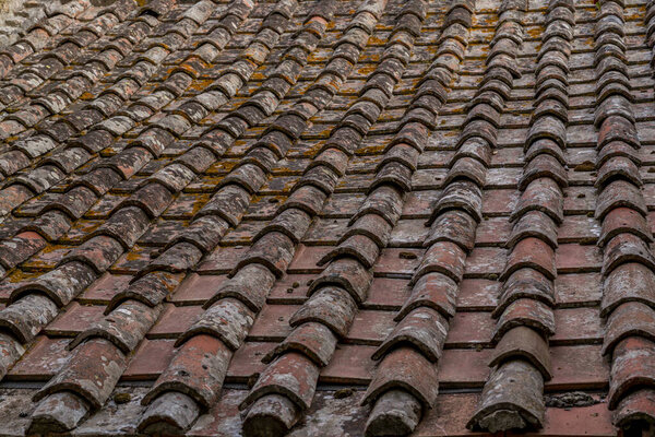 Деревенская крыша с изношенной терракотовой плиткой, с текстурой, деталями и исторической архитектурой.
