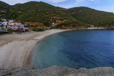 Sessiz hilal plajı, ağaçlarla kaplı Akdeniz tepelerinin altında berrak turkuaz denizle buluşur..