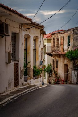Köy evleri, saksı bitkileri, balkonlar ve tepetaklak halatla çevrili asfalt sokak..