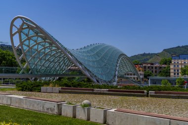 Kavisli cam ve çelik köprünün yan görüntüsü nehri gün ışığında kaplıyor..