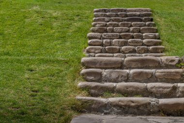 Huzurlu park yamacındaki yeşil çimlerin arasından taşralı taş merdiven çıkıyor.