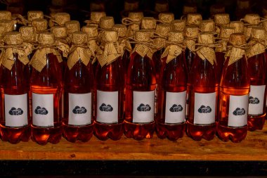 Süslü kağıt kapaklı pembe içecek şişeleri ve satır satır dizilmiş basit etiketler.