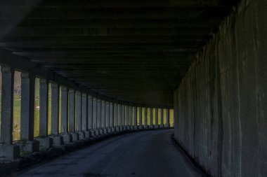 Huysuz dağ yolu tüneli, tekrar eden sütunlarla aydınlık gün ışığına çıkıyor.