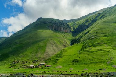 Engebeli yamaçların altında, parlak yeşil bir vadide, küçük bir çiftlik yerleşkesi yuva yapar..