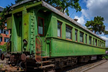 Yeşil zırhlı Stalin yolcu vagonu açık hava müzesinde, parlak yaz gökyüzünün altında demiryolu pistinde sergilendi..