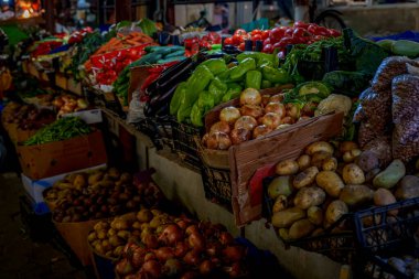 Bol miktarda biber, patlıcan, soğan ve patates kasaları kapalı alanda sebze pazarı görüntüsü oluşturur.