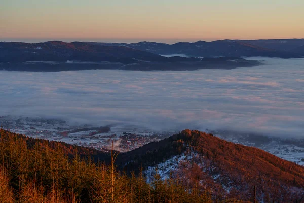 Karanlık dağ sırtları ve karlı vadileri olan bulutların üzerindeki ılık şafak vakti..