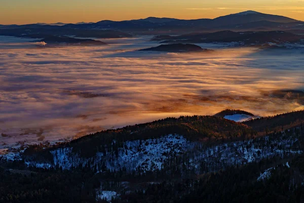 Güneşli sis tersine döner, karlı tepeler ve sıcak bir şafak vakti altında uzak tepelerle dağ vadileri boyunca akar..
