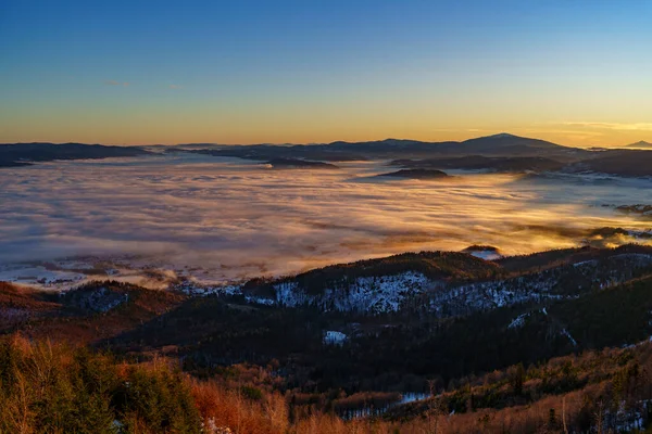 Şafak vakti sisi tersine çevirerek vadileri karlı tepeler ve açık bir gökyüzünün altındaki uzak tepelerle donatır..