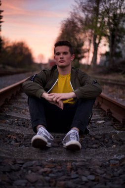 Demiryollarında poz veren genç bir adam. 
