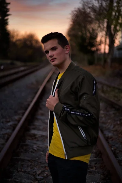 Demiryollarında poz veren genç bir adam. 