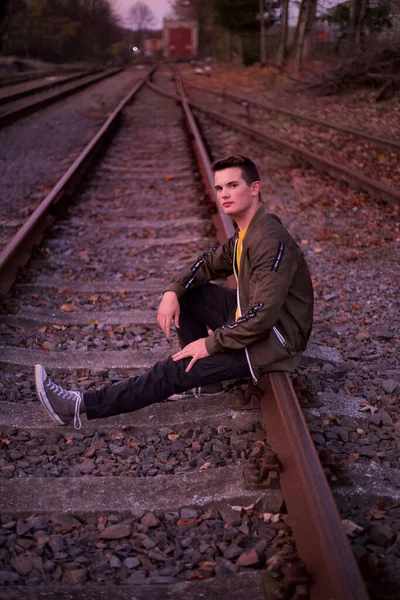 Demiryollarında poz veren genç bir adam. 
