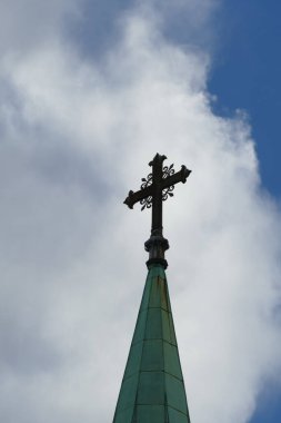 Arka planda dramatik bulutlar olan kilise kulesinde haç