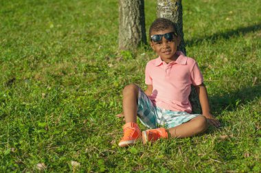 Çimenlerin üzerinde oturan Afro American boy