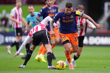 Newcastle United takımından Bruno Guimares, 9 Kasım 2025 'te Londra' daki Gtech Community Stadyumu 'nda oynanan Premier League karşılaşmasında baskı altında topa vuruyor. 