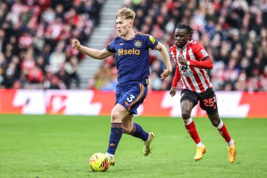 Lewis Hall of Newcastle United, Premier League karşılaşmasında Sunderland - Newcastle United Stadyumu, Sunderland, Birleşik Krallık 'ta 14 Aralık 2025' te Omar Alderete 'nin baskısıyla topu bırakıyor.