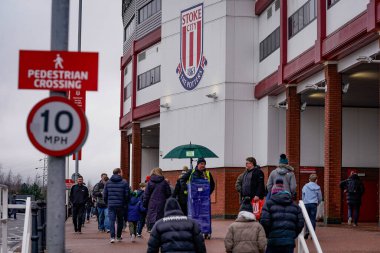 Taraftarlar, 15 Şubat 2026 tarihinde Birleşik Krallık 'ın Trent kentindeki Stoke On Trent Stadyumu' nda oynanan 4. Raund Stoke City - Fulham maçında resmi maç günü programlarını satan bir kahyanın yanından geçtiler.