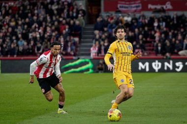 Ferdi Kadoglu of Brighton & Hove Albion passes the ball  while chased by Romelle Donovan of Brentford during the Premier League match Brentford vs Brighton & Hove Albion at GTECH Community Stadium, London, United Kingdom on 21 February 2026
