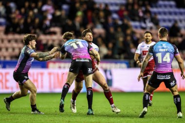 Ethan Havard of Wigan Warriors is tackled by Joe Batchelor of Hull FC and Cade Cust of Hull FC during the Betfred Super League match Wigan Warriors vs Hull FC at The Brick Community Stadium, Wigan, United Kingdom on 21 February 2026