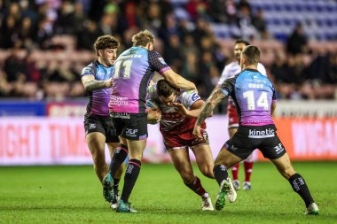 Ethan Havard of Wigan Warriors is tackled by Joe Batchelor of Hull FC and Cade Cust of Hull FC during the Betfred Super League match Wigan Warriors vs Hull FC at The Brick Community Stadium, Wigan, United Kingdom on 21 February 2026