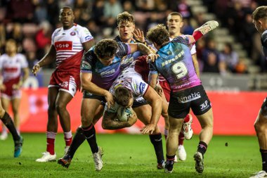 Kaide Ellis of Wigan Warriors is tackled by Harvie Hill of Hull FC and Amir Bourouh of Hull FC during the Betfred Super League match Wigan Warriors vs Hull FC at The Brick Community Stadium, Wigan, United Kingdom on 21 February 2026