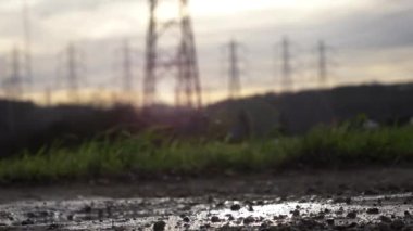 Statik akşam alçak açılı arazi yolu güç hattı değiştirme istasyonunda. Sağlam siyah çizmeli kadın ayaklarının görüntüsü..