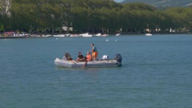 Annecy Gölü 'nde şişme botta oturup tatilin tadını çıkaran yavaş çekim turistleri. Seyahat aktiviteleri ve aile birliği kavramı..