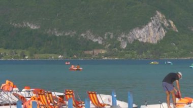Genç erkek işçi Fransa 'nın Annecy tatil beldesinde iş yerinde beyaz teknelerden can yelekleri topluyor.