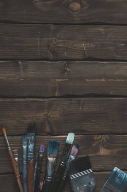 dirty brushes on brown wood background clipart