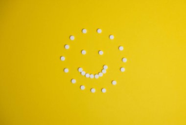 Sarı arkaplanda tabletlerden yapılmış bir yüz.