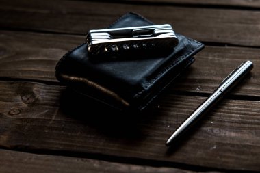 Cüzdan, metal tükenmez kalem ve kahverengi ahşap masada bir cep çoklu aracı. 