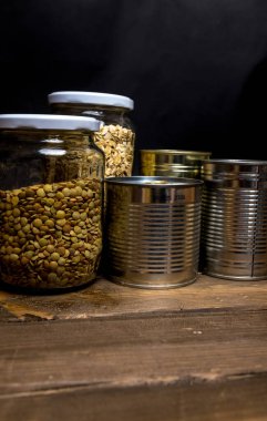 Mercimek kavanozu, yulaf ezmesi ve siyah arka planda teneke kutu.