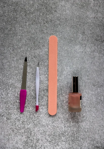 pink manicure tools and nail polish on gray background