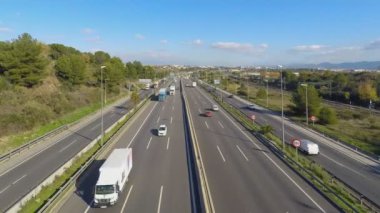 Birkaç şeritli ve ayrı şeritli bir otoyolun zaman çizelgesi. Hem arabaları hem de yolcu trenleri olan endüstriyel yük trenleri için bir tren yolu var. Uzakta bazı binalar var.. 