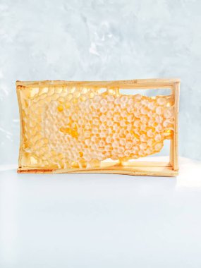 Balpeteği dolu bal hücreleri ve ahşap masa üzerinde ahşap bal kovanı. - Tatlım. Organik doğal bileşenler konsepti. Gri arkaplan 