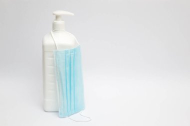 Bir kutu antiseptik dezenfektanın üzerine asılmış bir cerrahi maske..