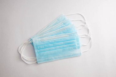 Beyaz arka planda dizilmiş dört açık mavi cerrahi maskesi..