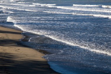 Güneşli bir günde dalgalar sahile vuruyor..
