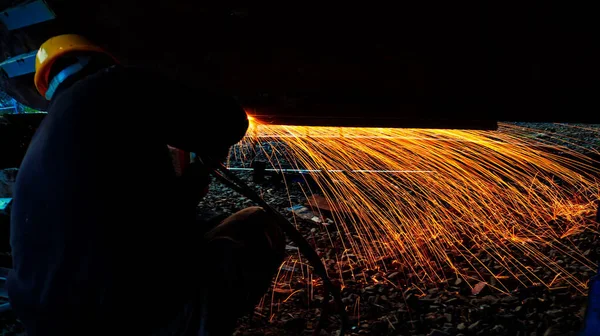 A welder is welding a part with a welding machine, it sparks sparks.