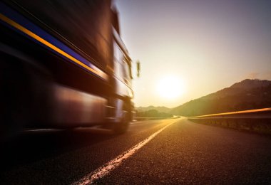 Yoldaki nakliye kamyonu. Kargo kamyonu asfalt yolda. Lojistik kamyonu gün batımında otoyolda hızla ilerliyor. Kargo kamyonu çok hızlı gidiyor..