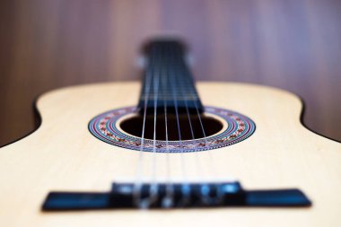 Klasik gitar ahşap zeminde duruyor. Klasik gitar ahşap arka planda yatıyor. Yakın plan. Arka plan bulanık..