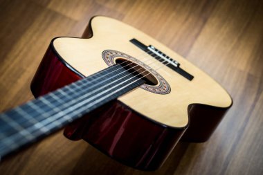 Klasik gitar ahşap zeminde duruyor. Klasik gitar ahşap arka planda yatıyor. Bulanık arka plan. Kırsal atmosfer..