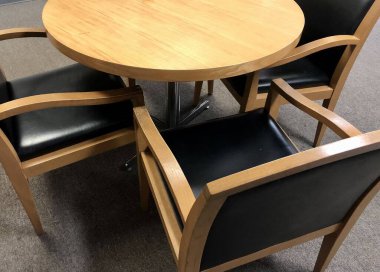 Basit ahşap sandalyeler ve tarafsız renklerde yuvarlak ahşap masa iş ortamı için uygun.