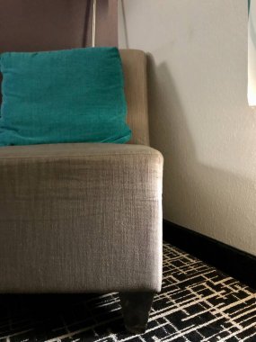 Otel odasının köşesinde sandalye yastığı ve lamba var.