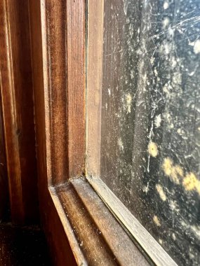 Yıpranmış pencere pervazının yakın çekim detayları ve konut binasının içerisindeki kirli pencere camı