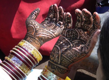 The womans hands are painted using the mihendi technique.