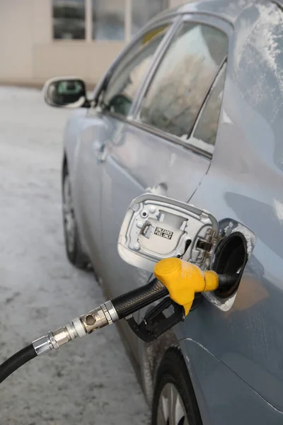 RefugiadoPistola de reabastecimiento de combustible en el tanque de gasolina de la carroza del coche en invierno. — Foto de Stock